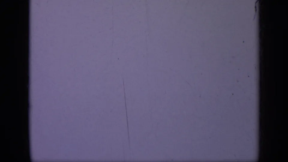 1962 Italy 8mm frame with a cool blue-purple exposure field, black gate edges, dust specks, and visible film wear.