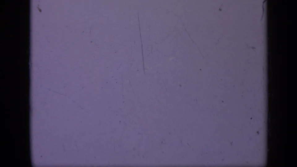 Purple-tinted 8mm leader or underexposed frame with visible film gate edges, grain, dust, and scratches from the 1962 Italy clip.