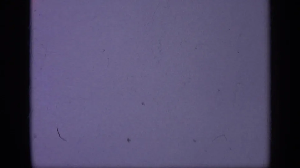 A tiny aircraft sits against the pale purple sky, with 8mm grain, dust, and edge shadowing from the film scan.