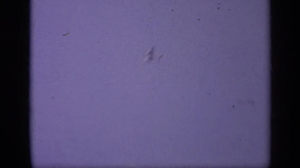 1962 8mm home-movie frame from likely Italy showing mostly pale sky, black gate edge, dust, and no identifiable subject.