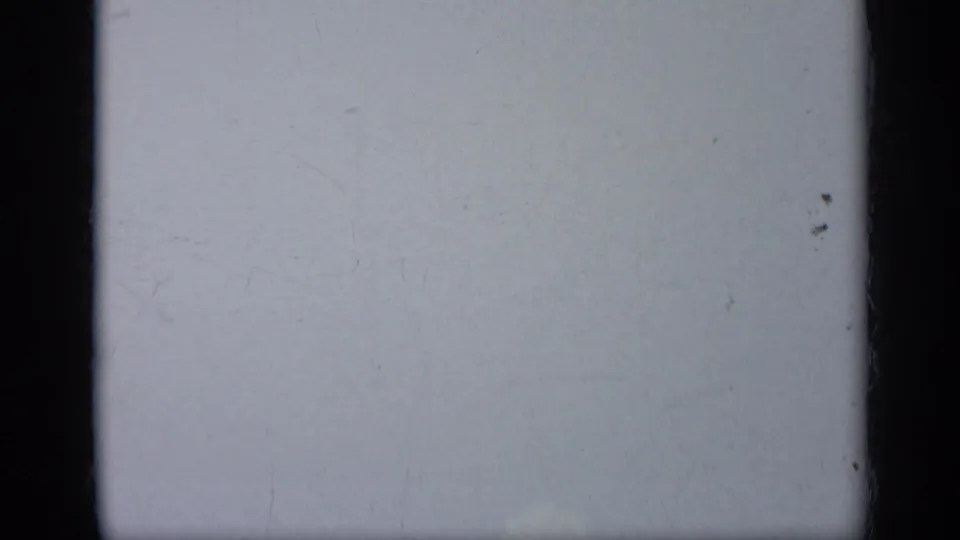Soft 8mm frame from the 1962 Italy clip showing pale sky, film wear, and dark vertical borders before the aircraft is clearly visible.