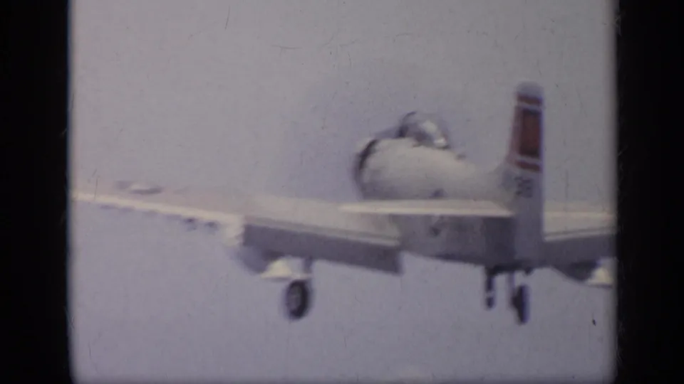 1962 Italy 8mm frame showing the white jet lifting from the carrier setting, with landing gear visible against pale sky and sea.