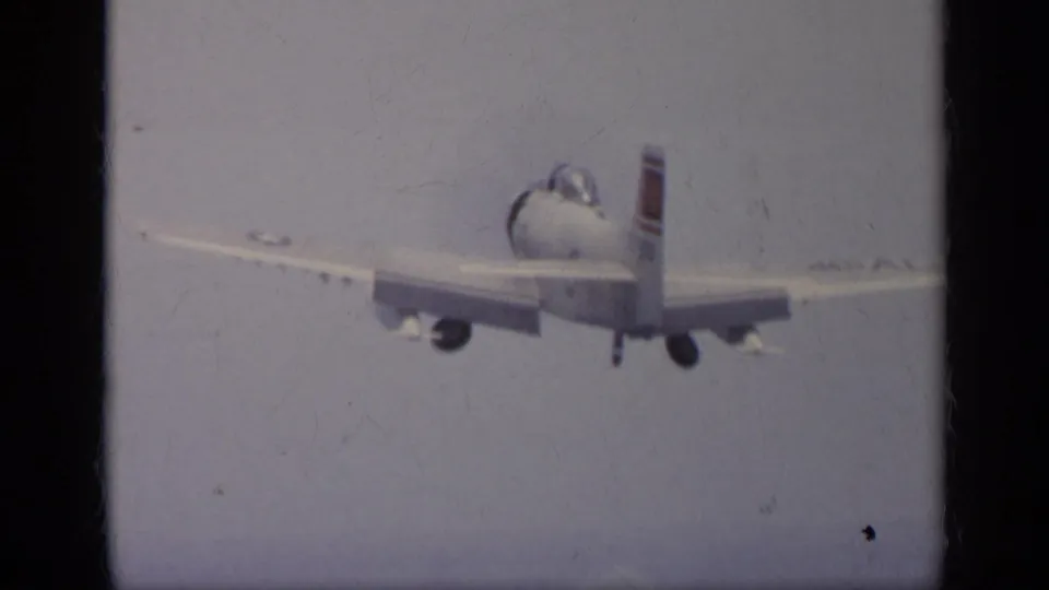 Rear view of a military jet in flight in archival 8mm footage, consistent with the supplied Italy 1962 carrier aviation metadata.