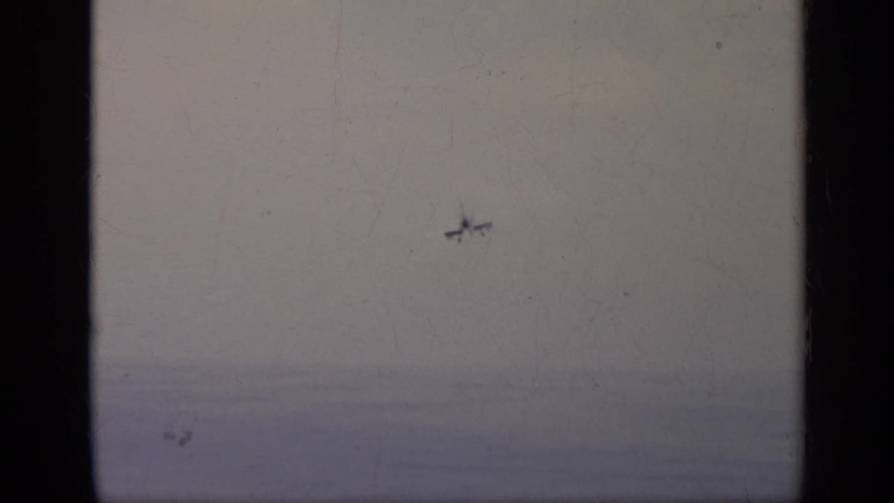 Distant aircraft appears over a hazy sky and horizon in this 1962 Italy aviation home-movie frame.