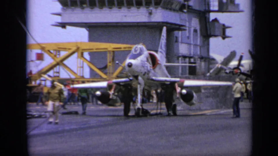 1962 Italy carrier-deck view of a military jet prepared for launch, with crew working around the aircraft.