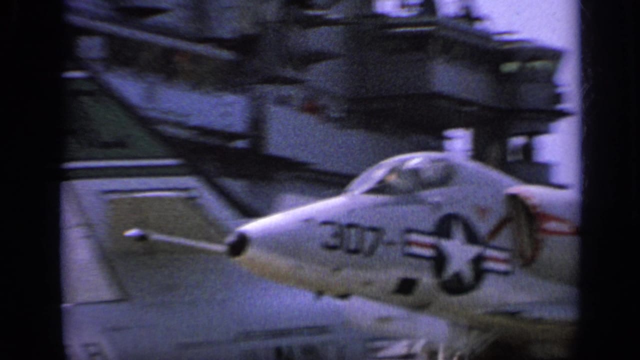 1962 8mm footage near Italy showing a U.S. Navy jet on a carrier deck, with crew and equipment partly visible around the aircraft.