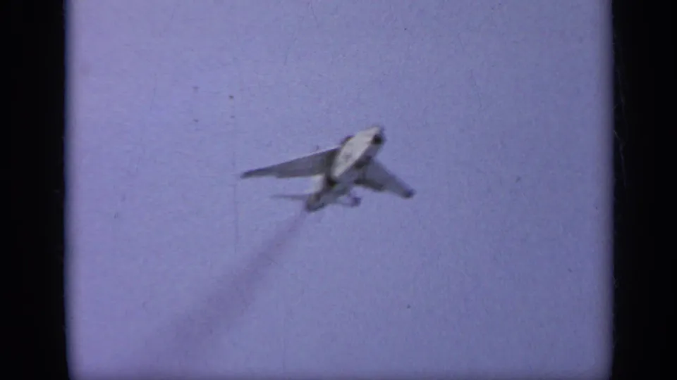 A jet fighter appears airborne or lifting away in the 1962 Italy carrier sequence, seen through grainy 8mm film texture.
