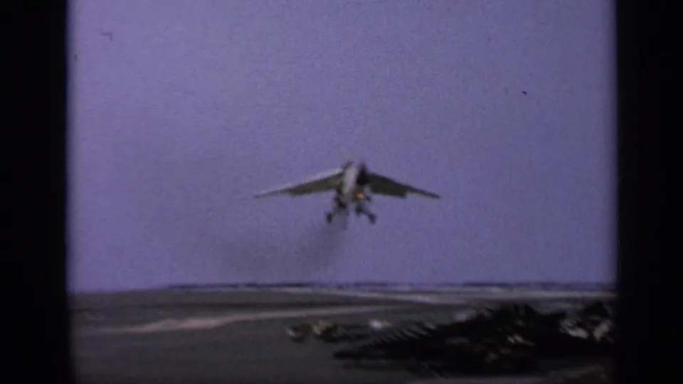 The jet nears touchdown on the aircraft carrier deck in a grainy 1962 8mm home-movie frame from Italy.