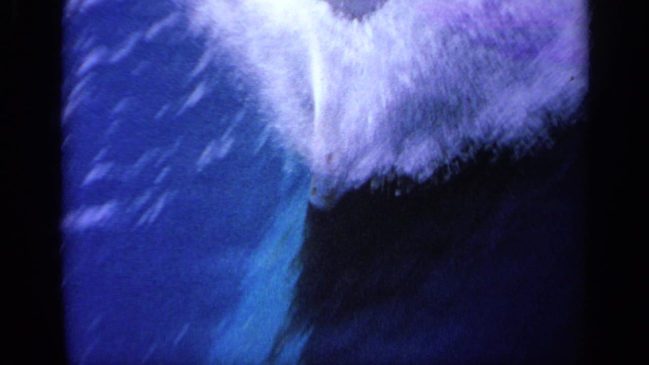 Close view of white boat wake beside deep blue water with dark film borders.