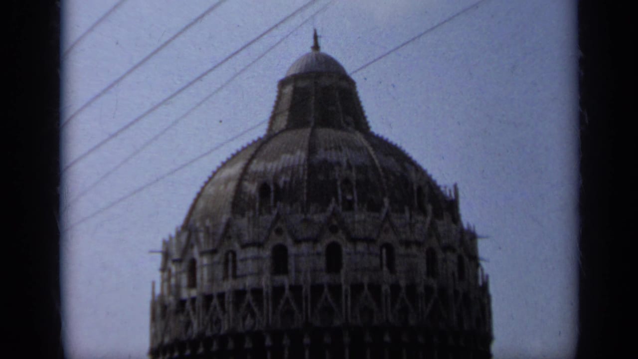 Upper section of the Leaning Tower of Pisa framed through dark film edges.