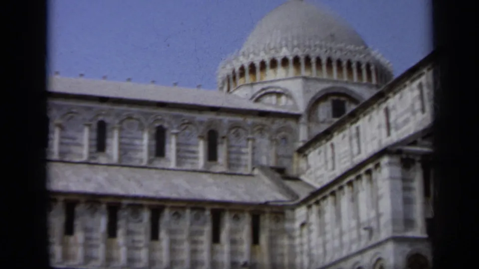 1962 Italy 8mm frame of Pisa Cathedral, with the dome rising behind a marble wall and rows of arched windows.