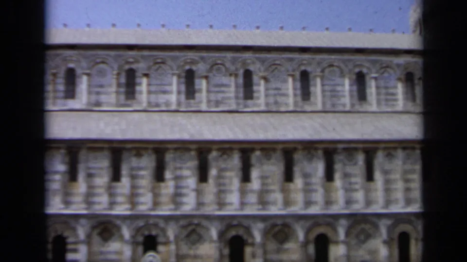 1962 Italy frame showing a long exterior wall of Pisa Cathedral with repeated arched windows and decorative marble arcades.