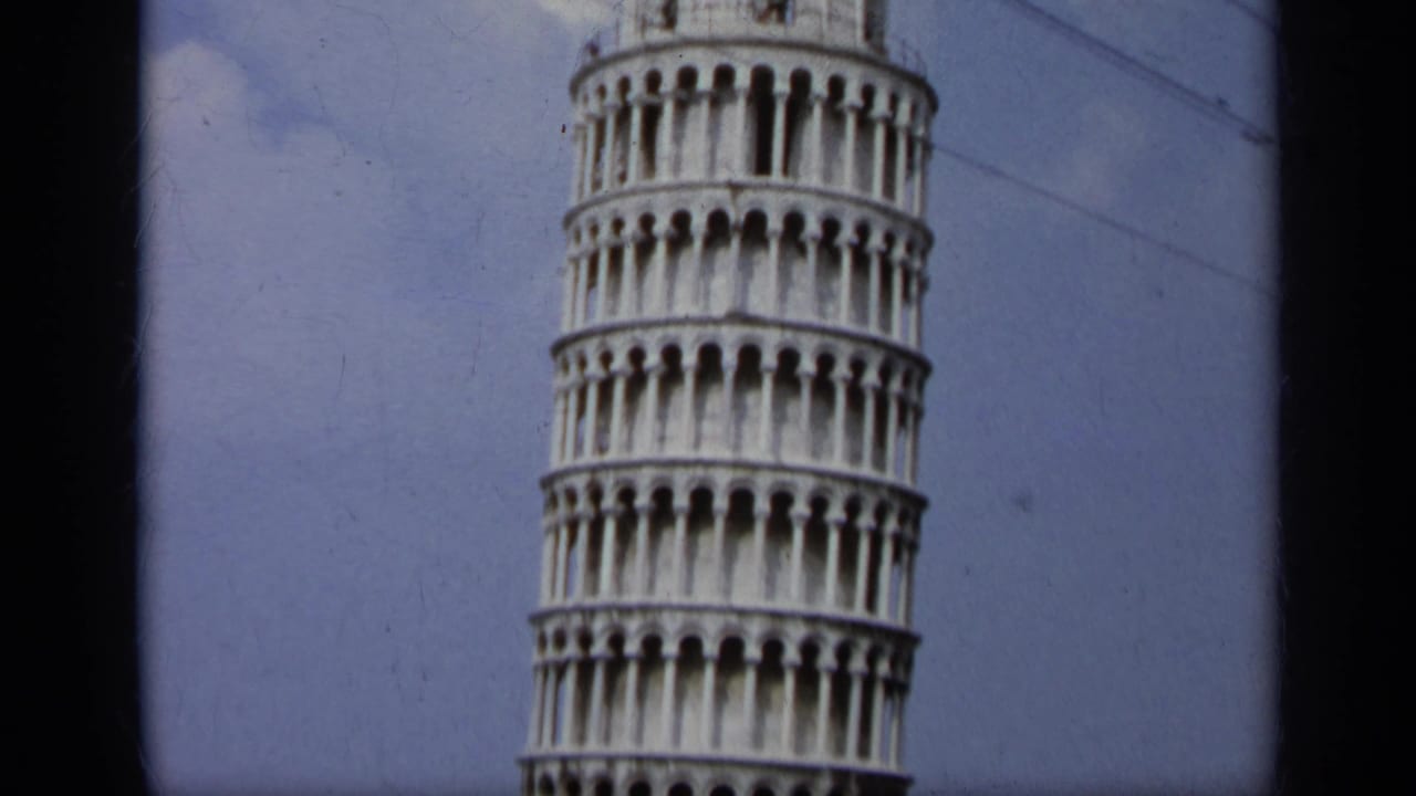 Partial close view of the Leaning Tower of Pisa against blue sky.