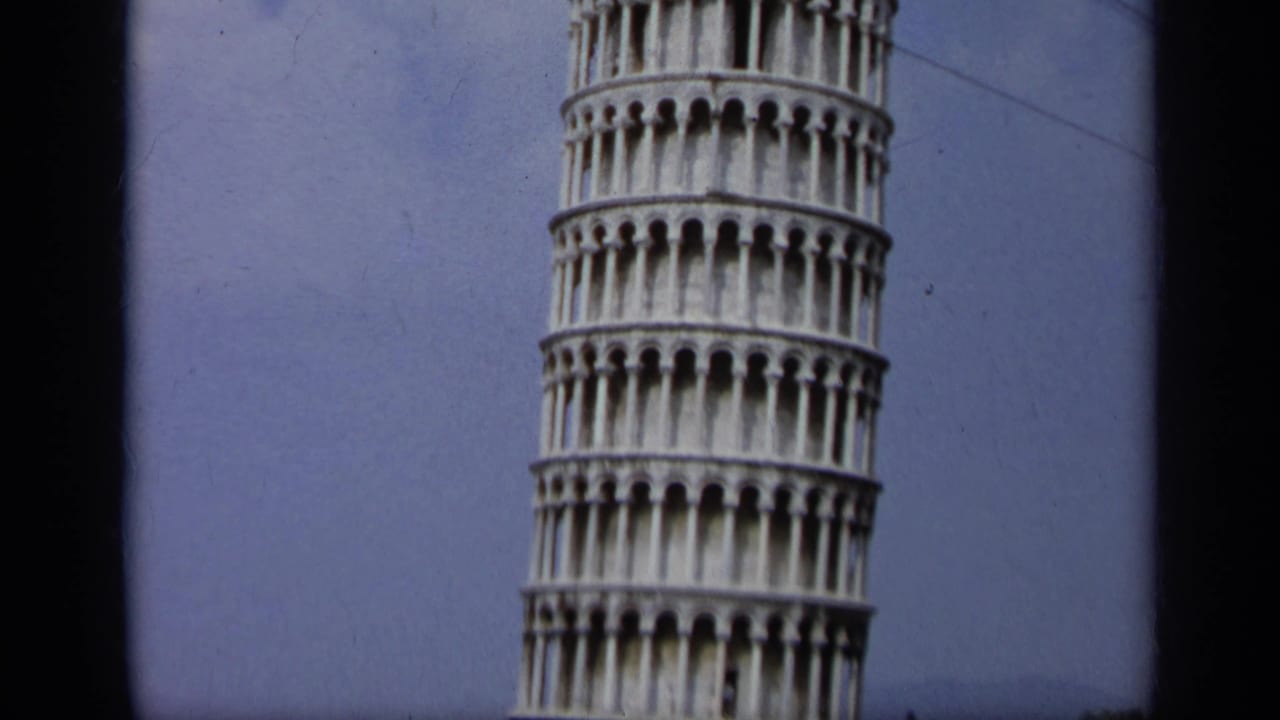 1962 8mm Italy footage shows the upper Leaning Tower of Pisa, arched galleries, blue sky, and dark frame edges.