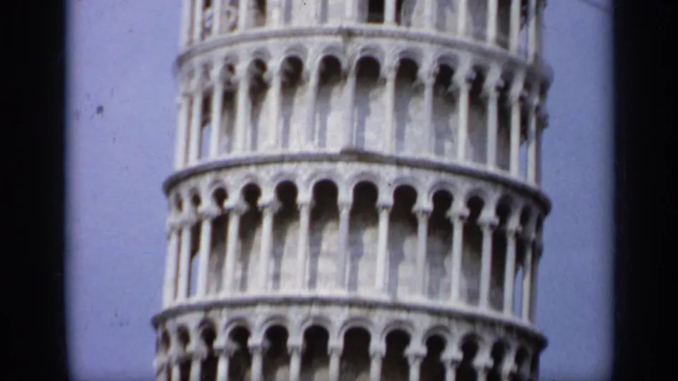 1962 8mm frame with a tight view of the Leaning Tower of Pisa's stacked arches and pale stone exterior.
