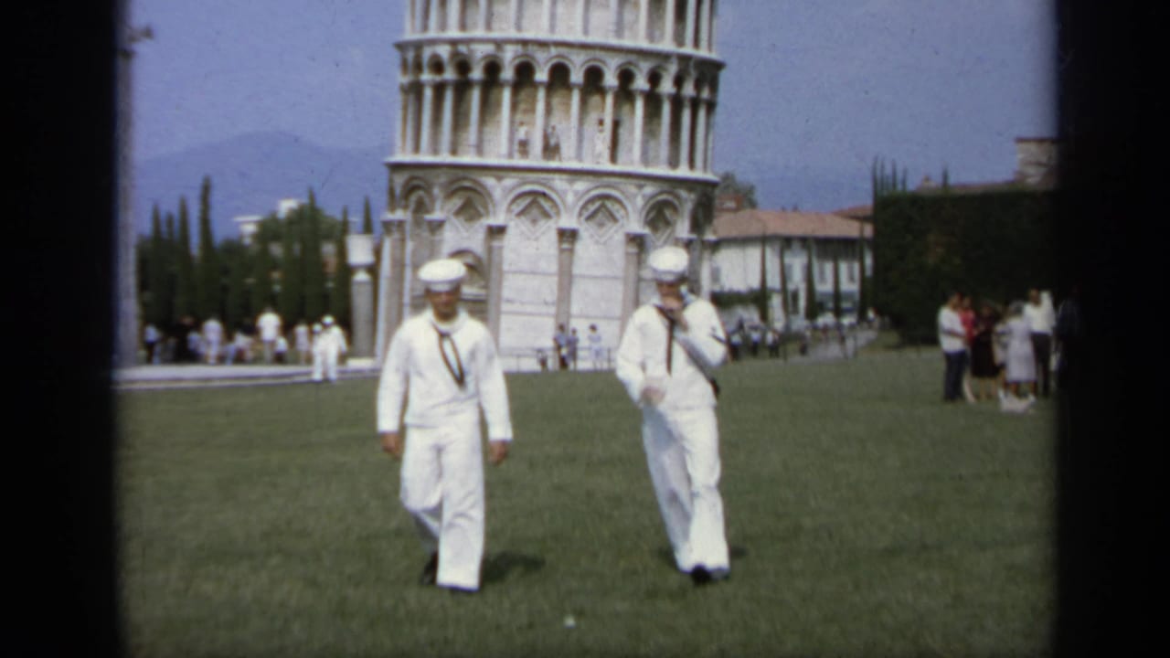 Two U.S. Navy sailors walk across a lawn in Pisa, Italy, with the Leaning Tower visible in the background, 1962.