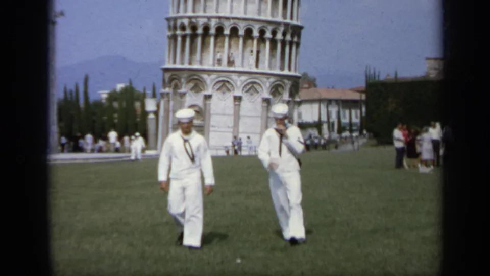 Two U.S. Navy sailors walk across a lawn in Pisa, Italy, with the Leaning Tower visible in the background, 1962.