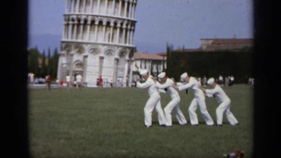 Home-movie frame from 1962 Italy with sailors in white uniforms forming a humorous line near the Leaning Tower of Pisa.