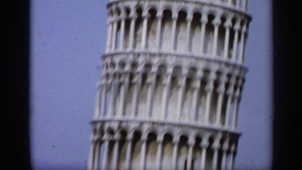 Close view of the Leaning Tower of Pisa against a blue sky.