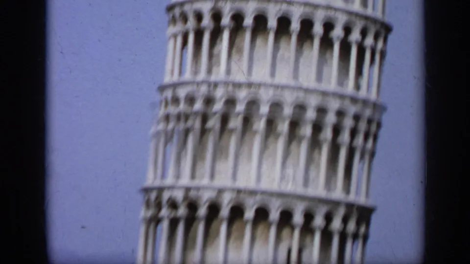 Close, soft 8mm view of the Leaning Tower of Pisa's arched tiers against the sky during an Italy travel shot.