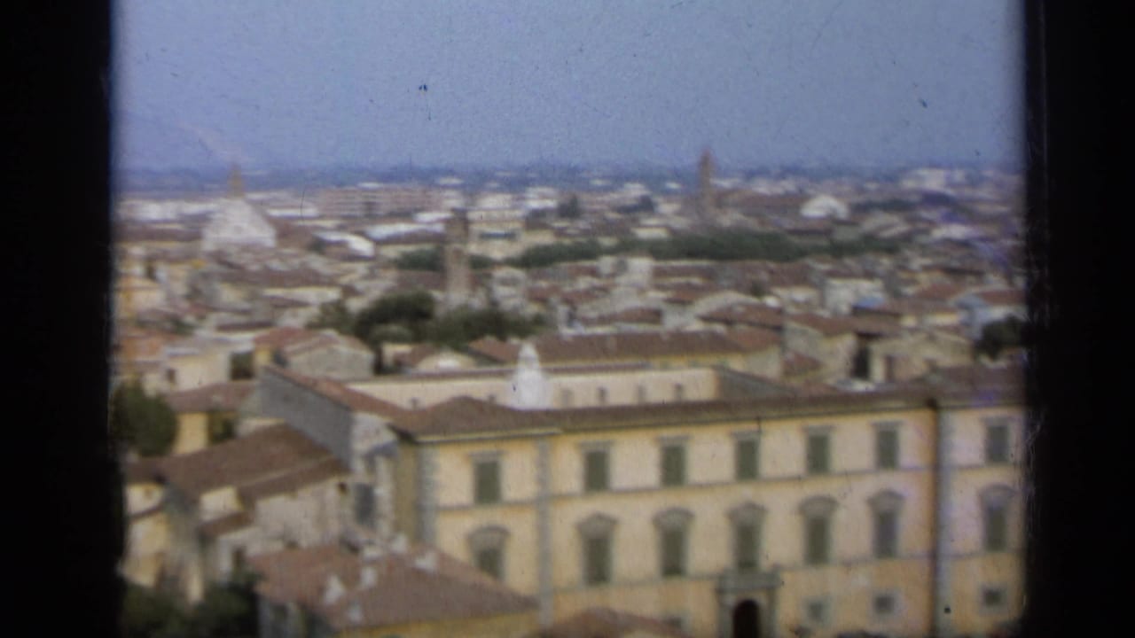 Elevated view across an Italian city with terracotta roofs and distant church domes.