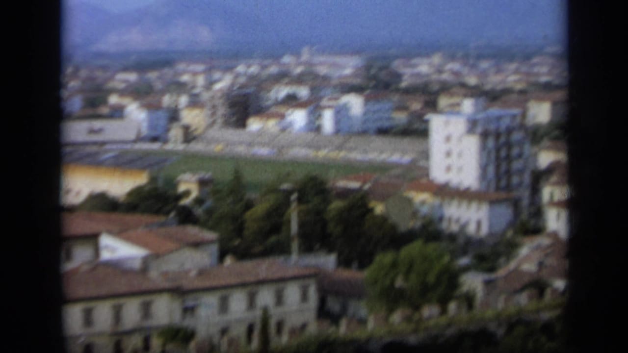 Soft elevated view across Assisi rooftops toward distant mountains.