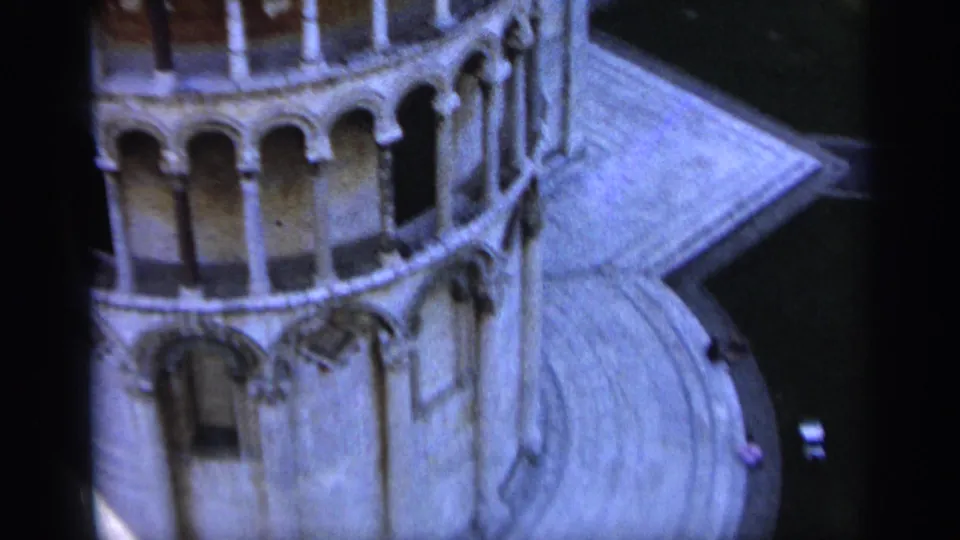 High-angle 1962 8mm view of the basilica exterior, showing rounded arches, pale stonework, and sloping roof surfaces.