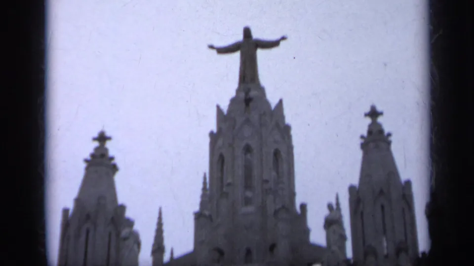 1962 Italy 8mm frame showing a Gothic-style church facade with crosses, spires, and a Christ statue with outstretched arms.