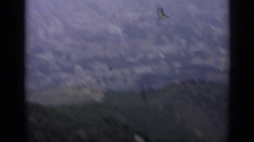 1962 Italy 8mm frame shifting away from the church toward cloudy sky and a distant hillside, with dark gate-like borders visible.