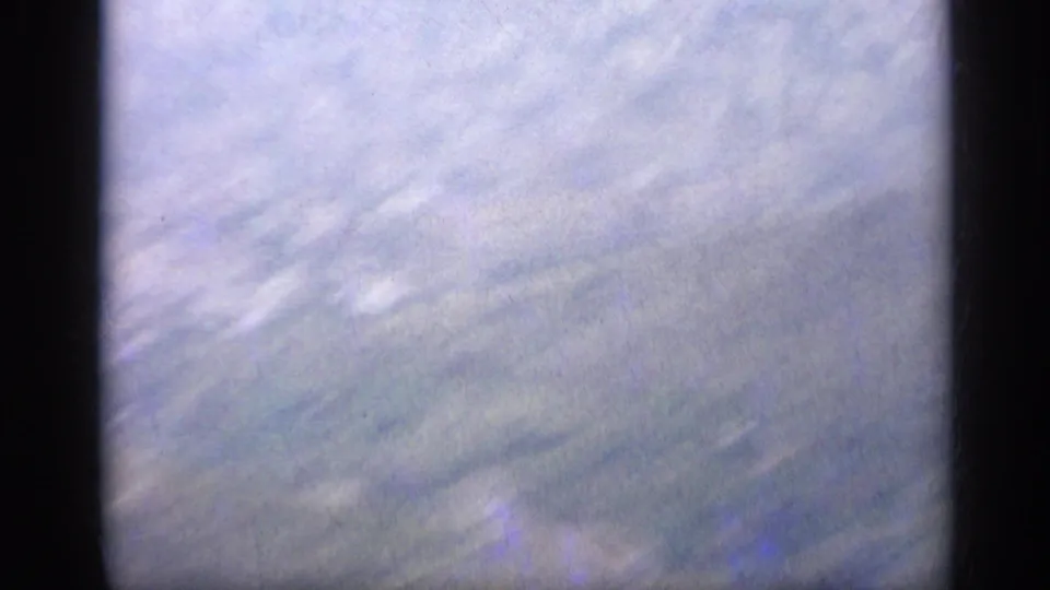 1962 Italy 8mm frame showing pale cloud cover and soft exposure, bordered by dark vertical film or camera-frame edges.