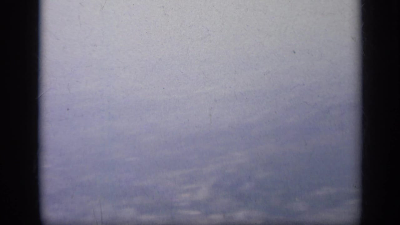 Blurred pale sky seen through dark vertical vehicle framing.