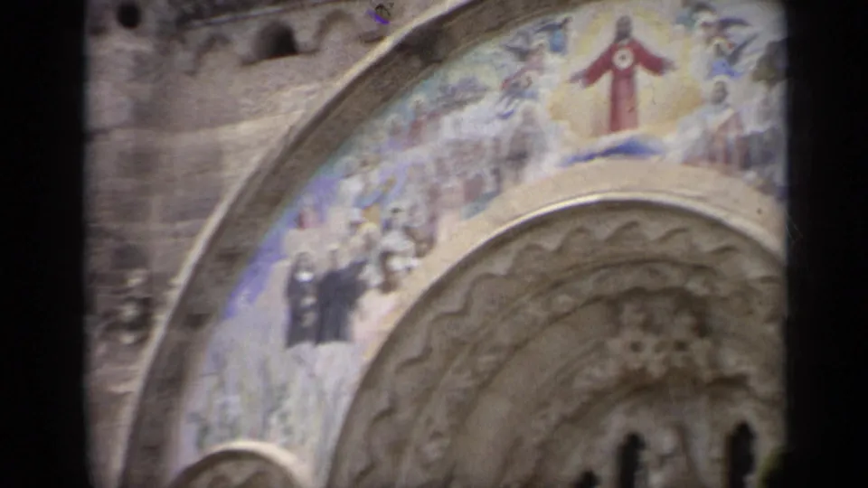 Italian church entrance with a colorful fresco of Jesus Christ and other religious figures above an ornate stone arch.