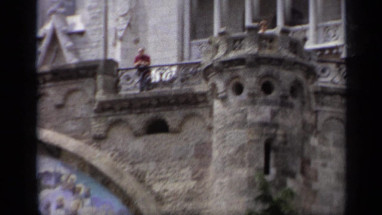 Ornate stone church facade with balcony, arched details, and a small person in red.