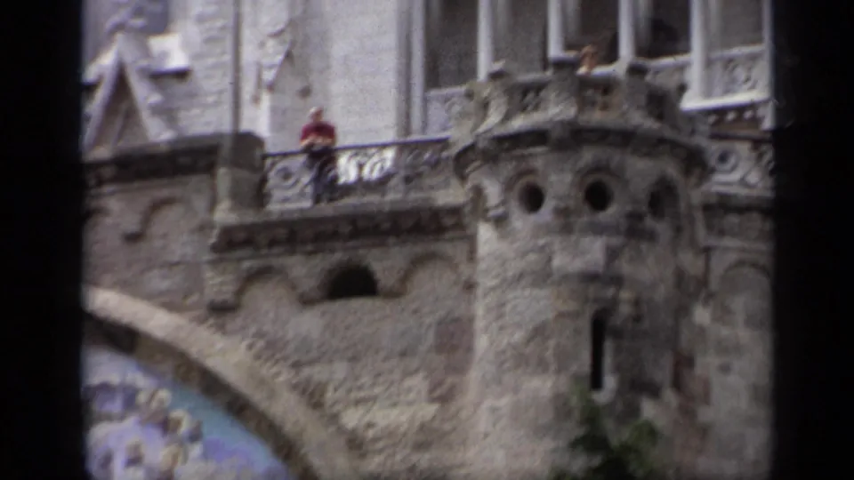 1962 Italy 8mm frame showing an ornate Gothic-style church facade, balcony railings, stone carvings, and a distant person in red.