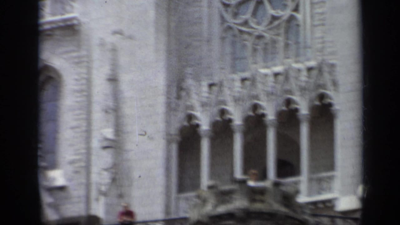 1962 Italy 8mm frame with carved stone windows, tracery, balcony architecture, and a small partly visible figure in red.