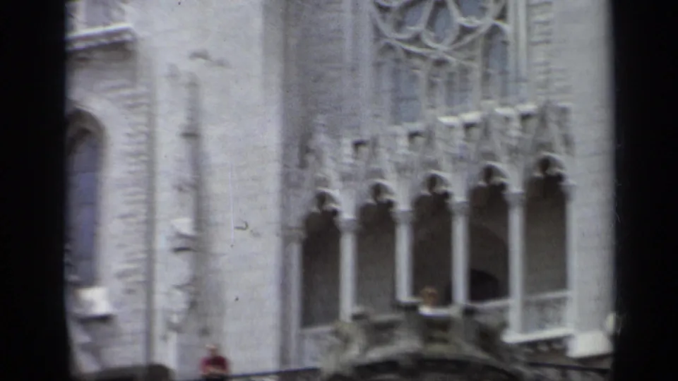 1962 Italy 8mm frame with carved stone windows, tracery, balcony architecture, and a small partly visible figure in red.