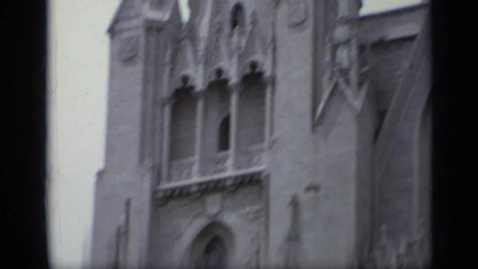 1962 Italy 8mm frame showing a section of ornate church wall with arched window openings, balcony trim, and a doorway.