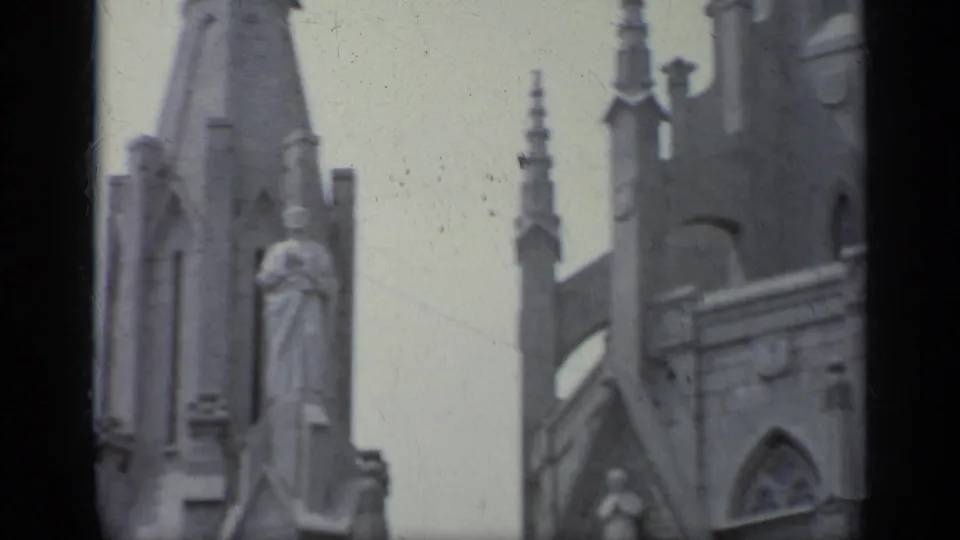 1962 Italy 8mm frame with church spires, statues, arched roofline, and carved stonework seen from below.
