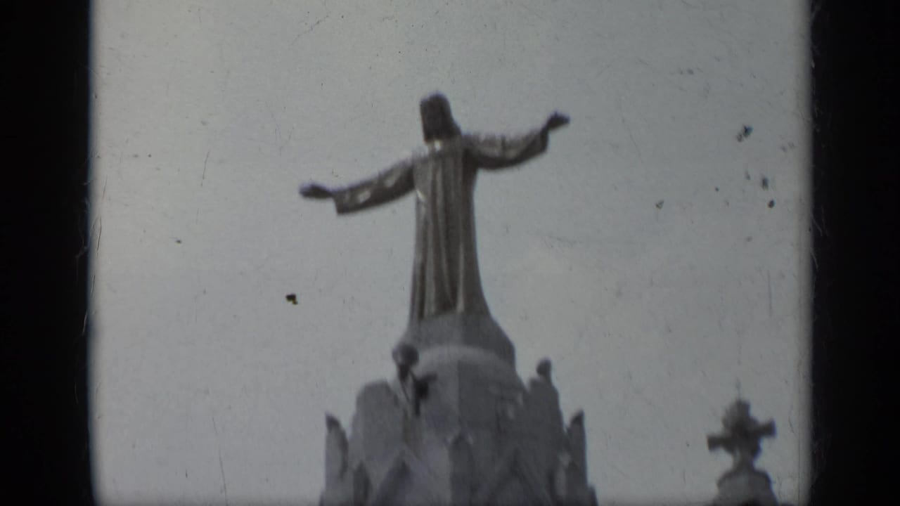 Rooftop statue with outstretched arms above a cathedral tower.