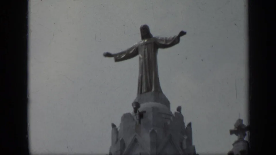 1962 Italy 8mm frame with the Jesus statue centered above Gothic stonework and pale sky, bordered by film gate edges.