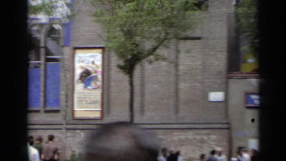 1962 Italy street scene with a bullfight poster on a brick building, a sidewalk tree, wall signs, and pedestrians along the lower edge.
