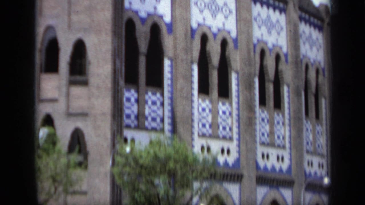 Close view of a decorated facade with arched windows and blue and white tile panels.