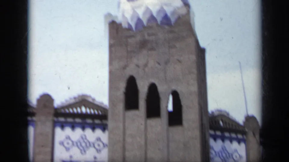 1962 Italy 8mm frame focused on a tower-like section with dark arches and blue and white decorative trim.