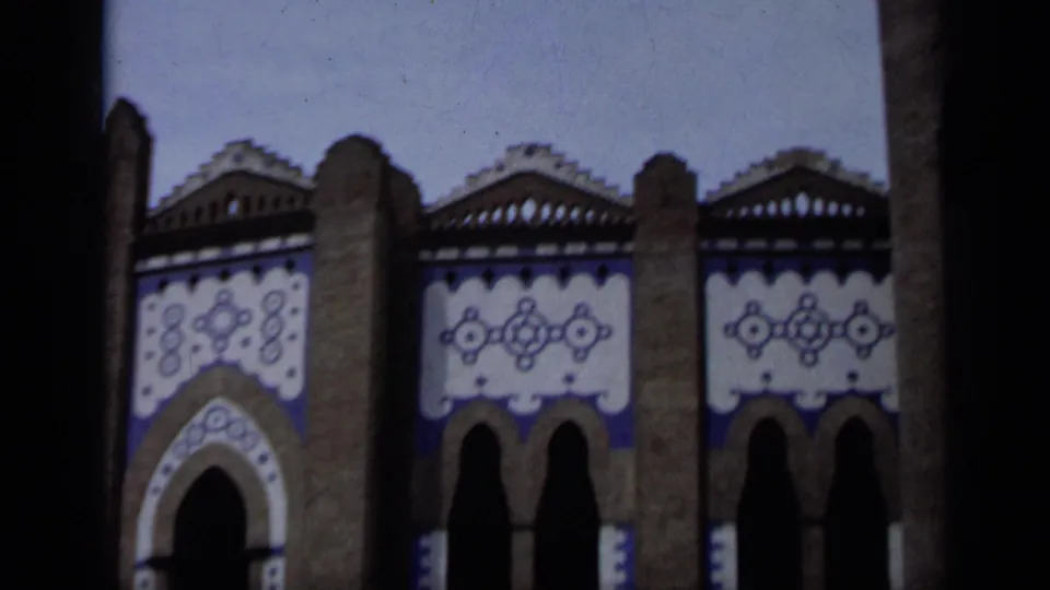 1962 Italy 8mm frame showing a lower roofline, paired arches, and bold blue and white geometric facade decoration.