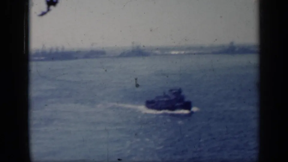1962 Italy 8mm frame showing a small industrial boat moving across choppy water with distant shapes on the horizon.