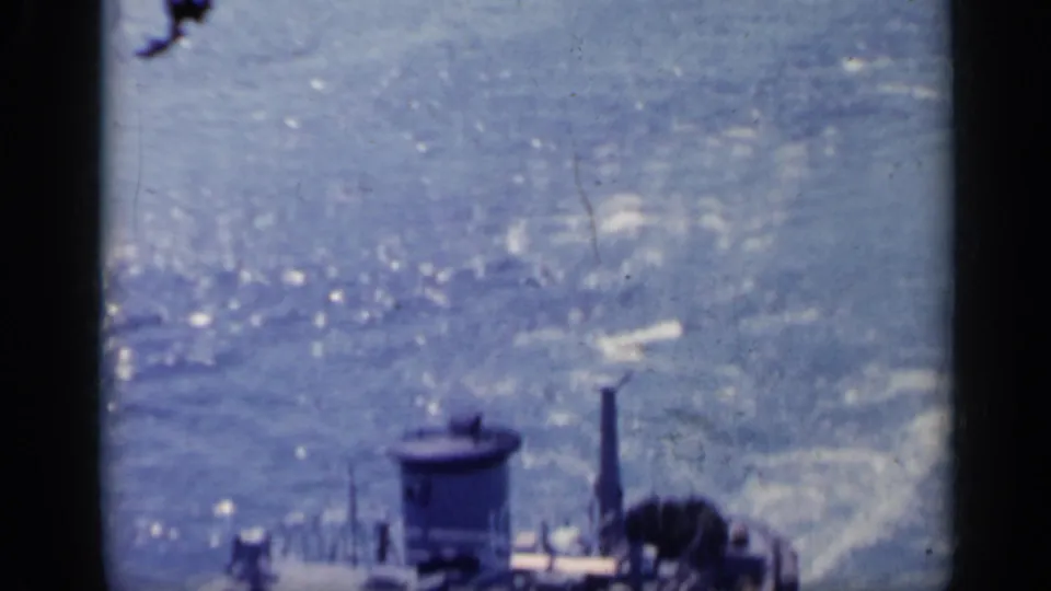 1962 Italy 8mm frame showing part of a small working boat at the lower edge with glittering, choppy water behind it.