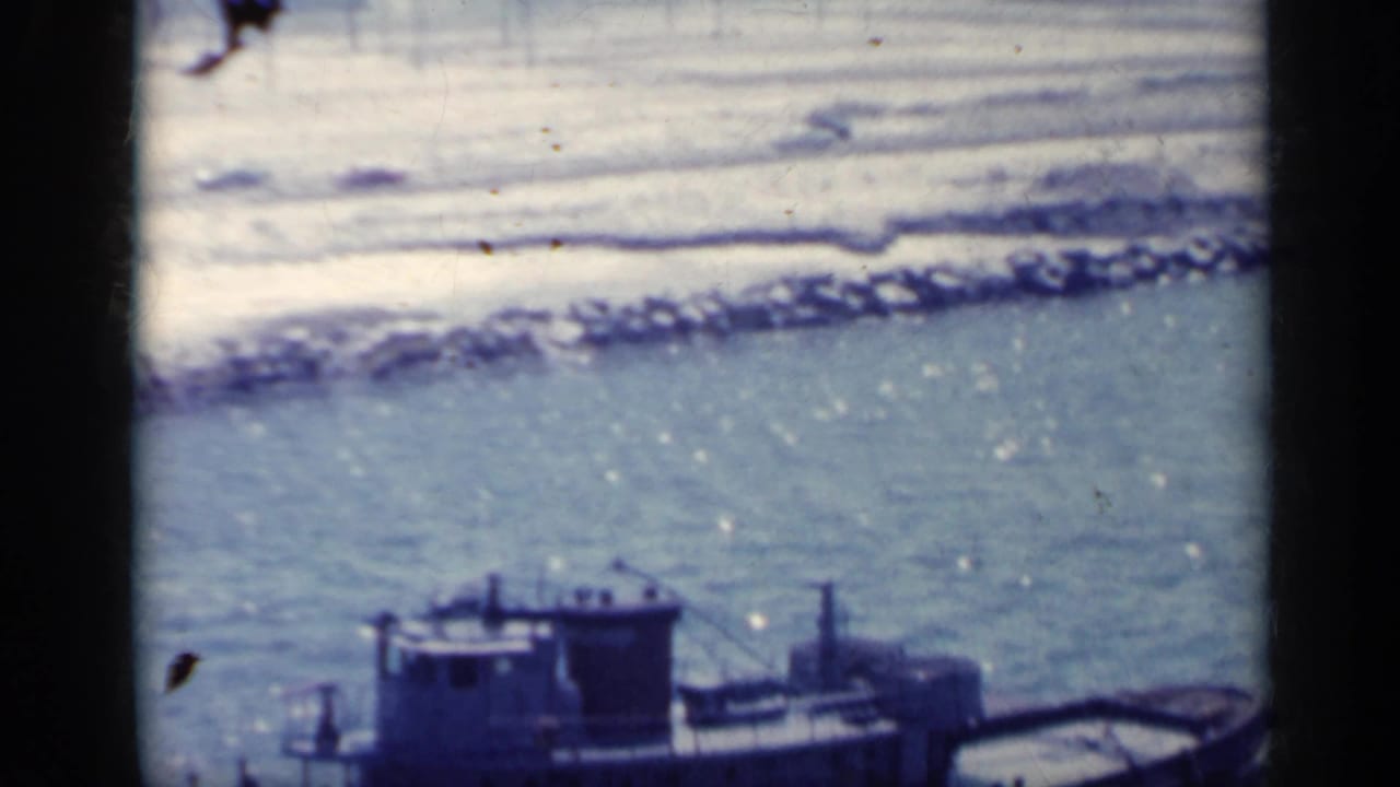 Large vessel partly visible on choppy blue water near a rocky shoreline.