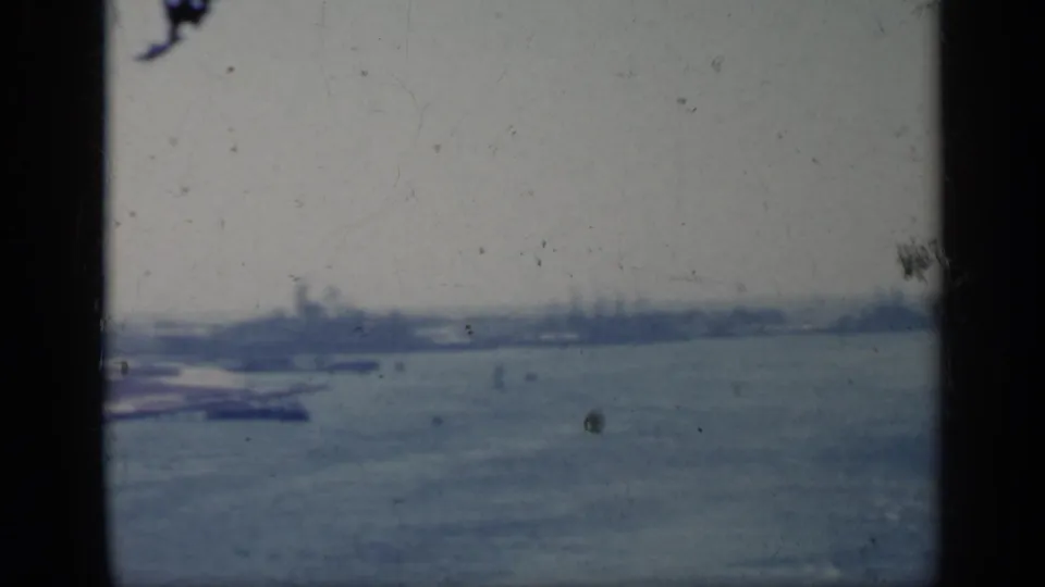 1962 Italy 8mm frame looking over open water toward a hazy shoreline with indistinct coastal structures.