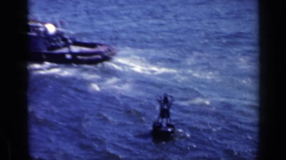 1962 Italian 8mm frame showing a small boat moving through choppy blue water with a buoy or marker in the foreground.