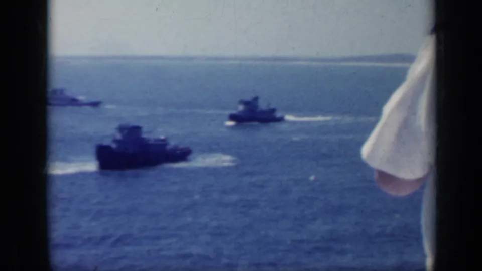 1962 Italy 8mm frame with support boats crossing open water and a partial white sleeve intruding from the right edge of the frame.